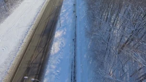 冬天在城市道路和森林之间的小道上慢跑的人的天线 无人机在雪堆中的步行道上飞行的一群运动员 健康的生活 冬季运动和健身 — 图库视频影像