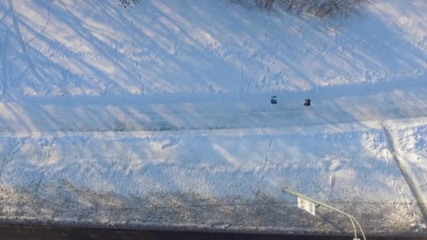 Aérea de personas que trotan en el parque de la ciudad entre las ventiscas de nieve en invierno — Vídeos de Stock