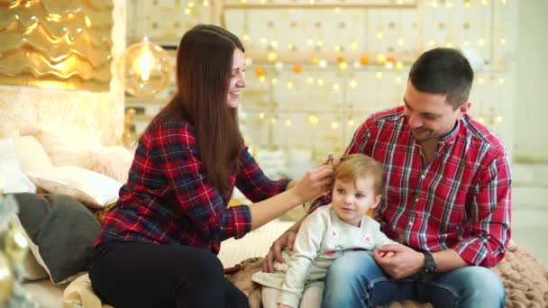 Jonge moeder doet kapsel voor haar peuter dochter en vader zit naast — Stockvideo