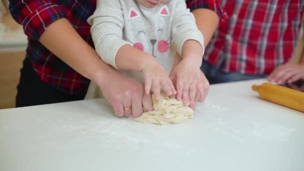 Young mother helps her little daughter to knead dough and father watching them — Stock Video