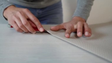 Erkek eller çökmekten duvar kağıdı rulo masada Kırtasiye bıçakla kesmek