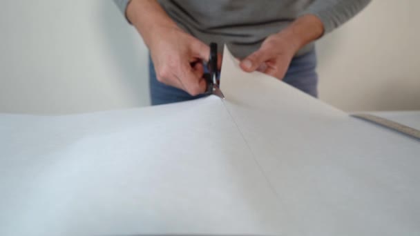 Primer plano manos masculinas corte nuevo doblado papel pintado rollo con tijeras en la mesa interior — Vídeo de stock