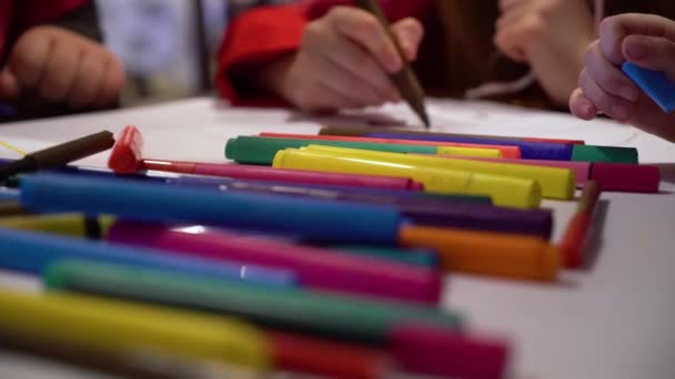 Детская группа крупным планом рисует вместе на большой бумаге с акцентом на цветные маркеры — стоковое видео