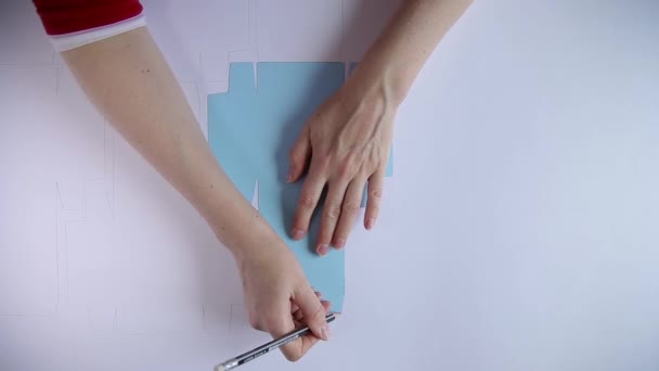 Vista superior de las manos de la mujer plantilla de contorno con lápiz en hoja grande de papel — Vídeo de stock