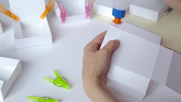 Femme mains coller modèle de boîte en papier et détails de serrage avec pinces à linge gros plan — Video