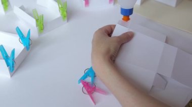 kadın closeup yapıştırma kağıt kutusu şablonu ve sıkma ayrıntıları clothespins ile eller.