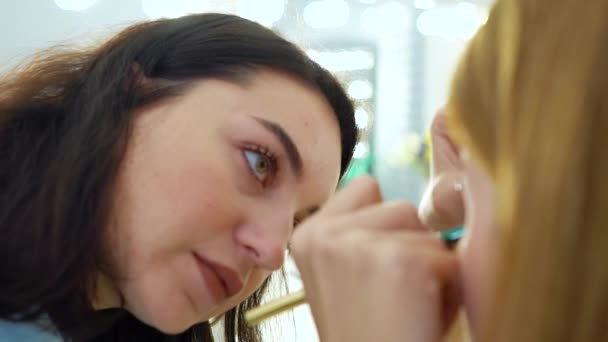 Primer plano de artista de maquillaje haciendo maquillaje para mujer de pelo rojo en cámara lenta — Vídeos de Stock