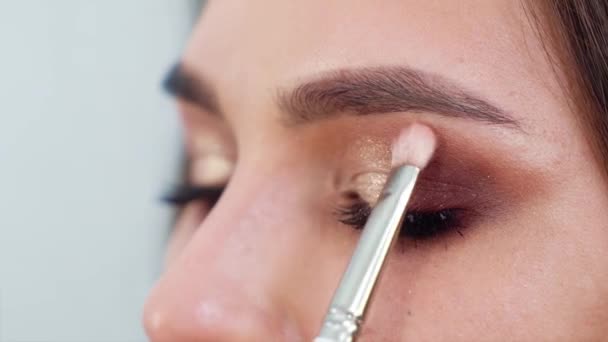 Крупный план лица молодой женщины, получающей профессиональный макияж в замедленной съемке — стоковое видео