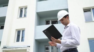 İnşaat sitesi mühendis tablet denetimi yapı teknolojisi ile işlem. Kask içinde erkek mimar iş akışı açık havada denetler. Bina, sanayi, emniyet konsepti