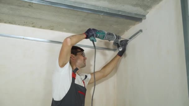 Constructores masculinos usando taladro eléctrico ensamblando perfiles de paneles de yeso metálicos en el sitio de construcción en interiores — Vídeos de Stock