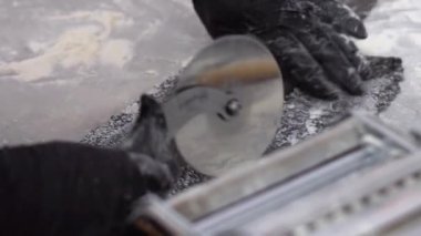 ellerinde eldiven kesim ağır çekimde pizza bıçak closeup ile siyah hamur rulo