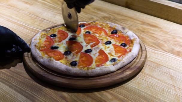 Різання свіжої запеченої піци з колісним ножем і додавання на нього олії в повільному русі — стокове відео
