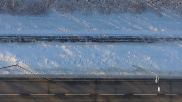 Aérien de personnes faisant du jogging sur un sentier enneigé près de la route de la ville en hiver — Video