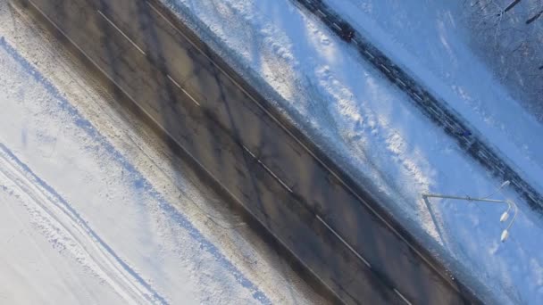 Aerial of sportsmen running on snowy path near city road in winter — Stock Video