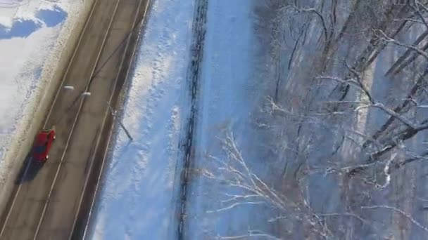 Aerial of people jogging on path between city road and forest in winter — Stock Video