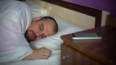 Genç adam yatakta uyuyor.