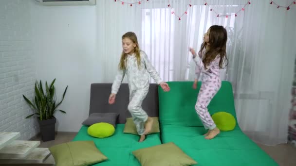 Girls in pajamas dancing on sofa — Stock Video