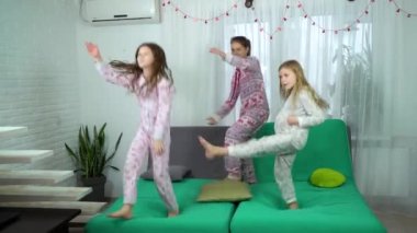 Üç sevimli kız koltukta dans pijama. Çocuklar evde birlikte eğleniyor. dostluk, çocukluk ve boş zaman zaman