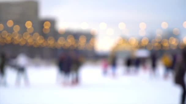 Verschwommene Sicht auf Menschen, die im Winter auf der Eisbahn unter freiem Himmel Schlittschuh laufen — Stockvideo
