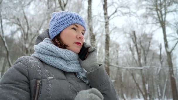 Mujer adulta hablando por teléfono en el parque de invierno — Vídeos de Stock
