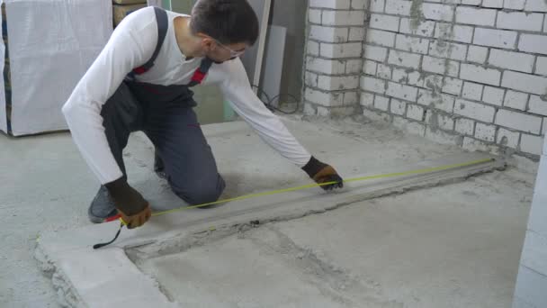 Bouwer maatregelen afstanden met het meten van de tape en potlood op bouwplaats — Stockvideo