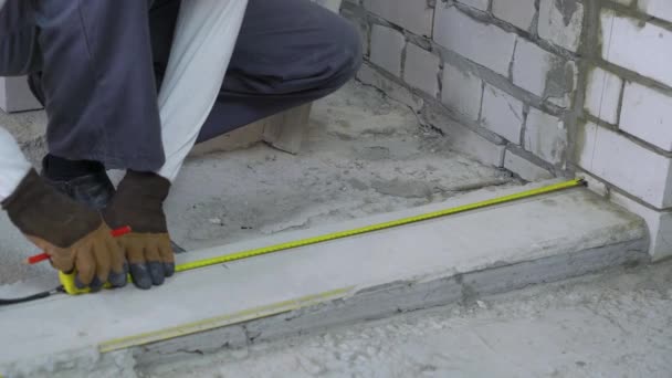 Builder doing measures with measuring tape and pencil at construction site — Stock Video