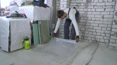 İşyeri inşaat sahasında temiz tutmak. Üniforma, eldiven ve koruyucu gözlük koyarak Builder'da beton bloklar şeffaf plastik kapak üzerinde gazlı. İnşaat, iç ve temizlik