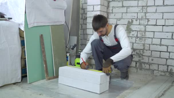 Trabajador de la construcción haciendo marcado en bloque de hormigón aireado en el sitio de construcción — Vídeo de stock