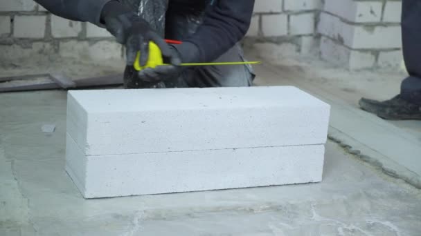 Travailleur de la construction sciage bloc de béton aéré après l'avoir mesuré — Video