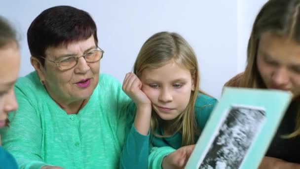 Babička zobrazeno staré fotoalbum k její čtyři vnučky — Stock video
