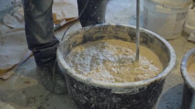İnşaat işçisi sıva çözüm elektrikli karıştırıcı ile karıştırma closeup