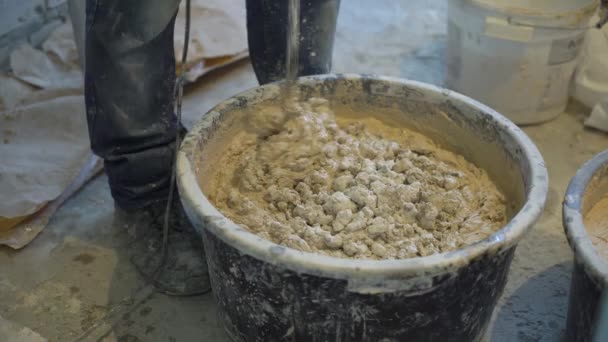 Construction worker mixing plaster solution with electric mixer — Stock Video