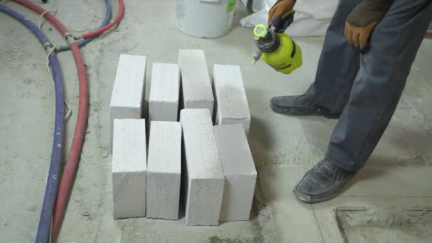 stavební dělník moisturing pórobetonu betonových bloků s vodou postřikovače