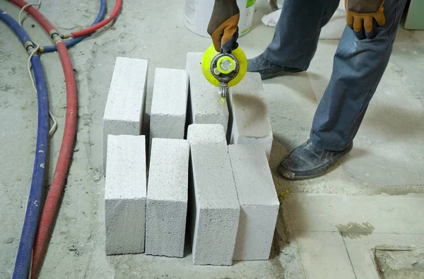 Travailleur de la construction humidifier blocs de béton aéré avec pulvérisateur d'eau — Photo