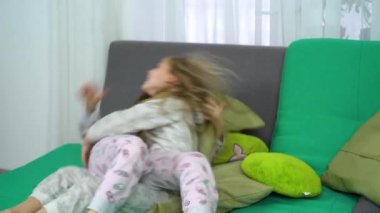 iki küçük kız kanepede eğlenmek için mücadele