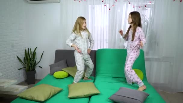 Iki küçük kız koltukta dans pijama — Stok video