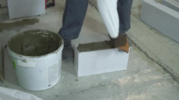 Builder putting mortar on side of aerated concrete block with spatula — Stock Video