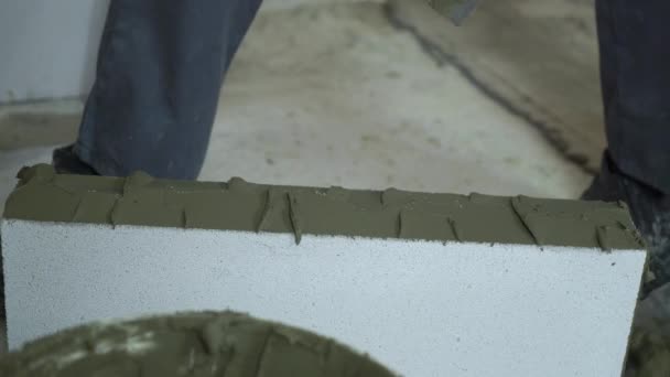 Bauarbeiter setzt Mörtel mit Spachtel auf Porenbeton — Stockvideo