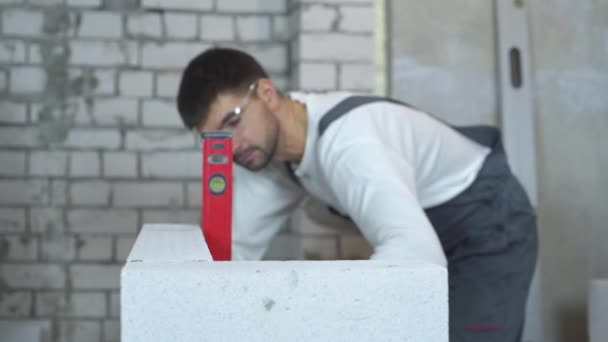 İnşaat işçisi düzgünlüğünü duvar kabarcık seviyesi ile kontrol — Stok video