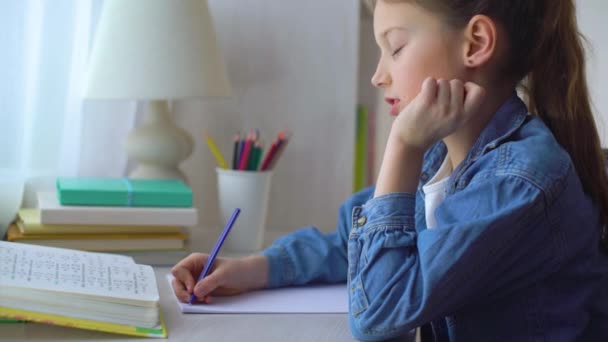 Kleines Schulmädchen macht Hausaufgaben am Tisch — Stockvideo