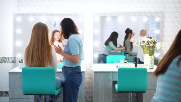 Panorámica de chicas de salón de belleza haciendo maquillaje y peinado a los clientes — Vídeos de Stock