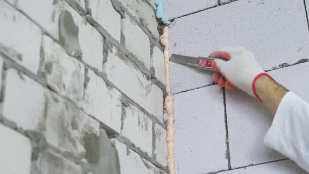 Closeup of builder removing excessive mounting foam between walls — Stock Video