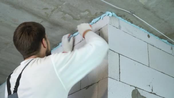 Construtor removendo espuma de montagem excessiva entre parede e teto — Vídeo de Stock
