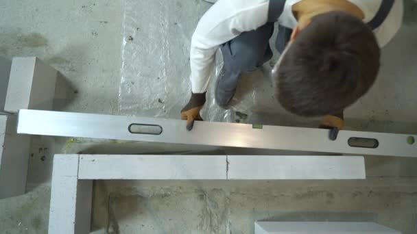 Vista superior do construtor verificando a uniformidade da parede de concreto aerado com nível de bolha — Vídeo de Stock