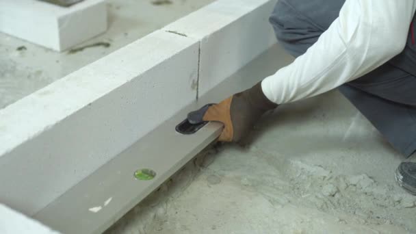 Trabajador de la construcción comprobando la uniformidad de la pared de hormigón aireado con nivel de burbuja — Vídeo de stock