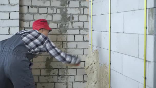 Construtor em gesso de colocação uniforme na parede do bloco de concreto aerado — Vídeo de Stock