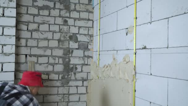 Bauarbeiter in Arbeitskleidung kleben Gips auf Porenbetonsteinwand — Stockvideo
