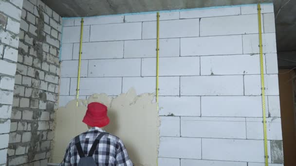 Οικοδόμος ισοστάθμιση σοβά σε αεριούχο τσιμεντένιο τοίχο μπλοκ με κατασκευή χάρακα — Αρχείο Βίντεο