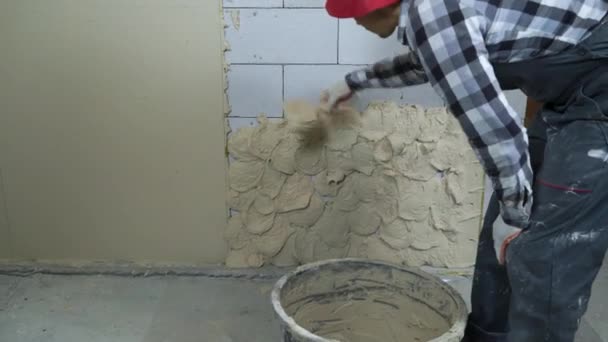 Οικοδόμος στο φορούν την εργασία βάζοντας σοβά σε αεριούχο τσιμεντένιο τοίχο μπλοκ — Αρχείο Βίντεο