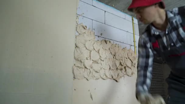 Construtor em desgaste de trabalho colocando gesso na parede do bloco de concreto aerado — Vídeo de Stock